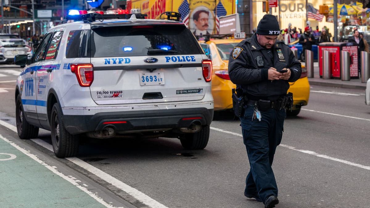 An NYPD police officer walking using his cell phone