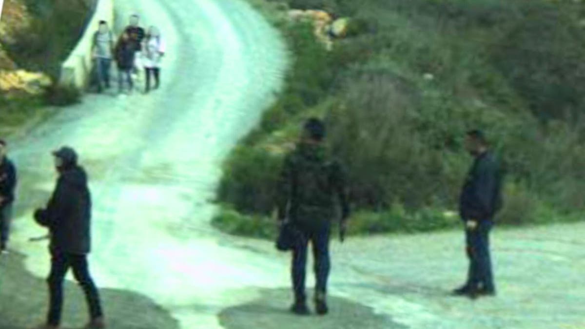 A man with a gun watched as migrants approach