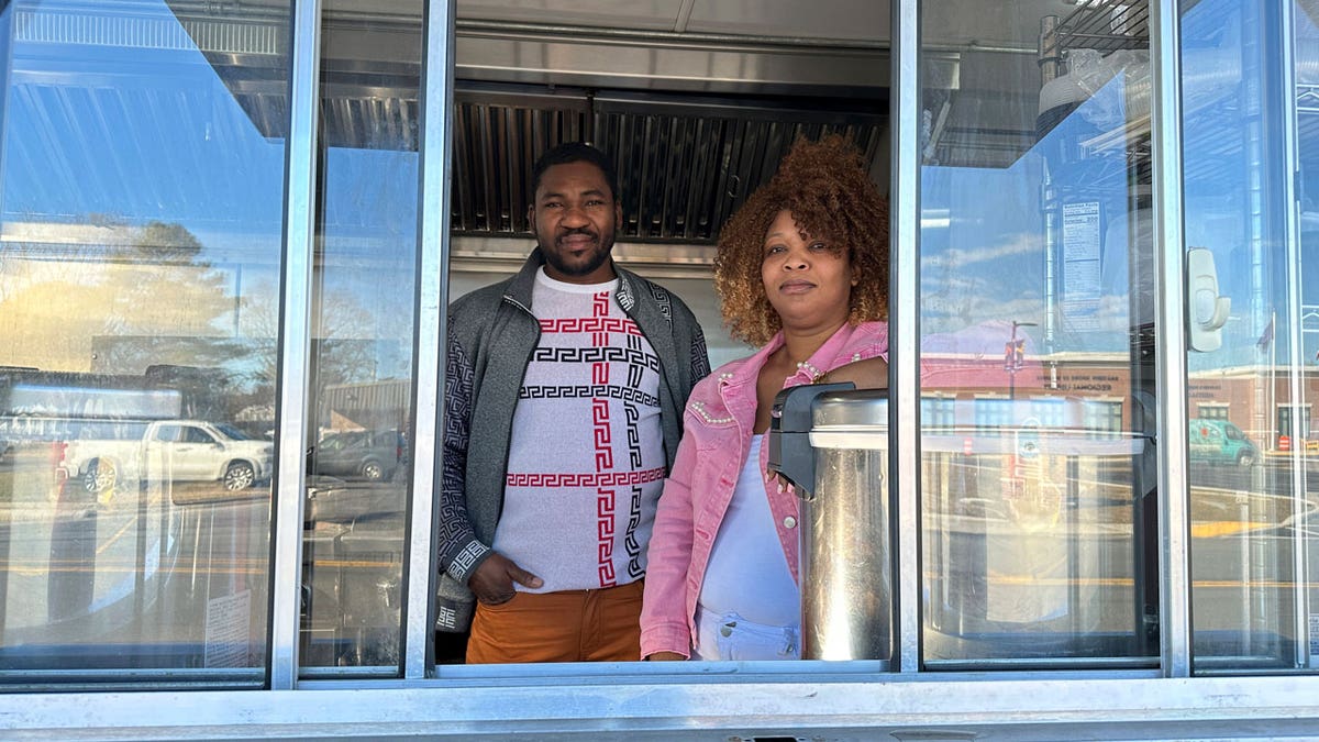 Theslet Benoir and Clemene Bastien stand at the window of their Eben-Ezer Haitian food truck