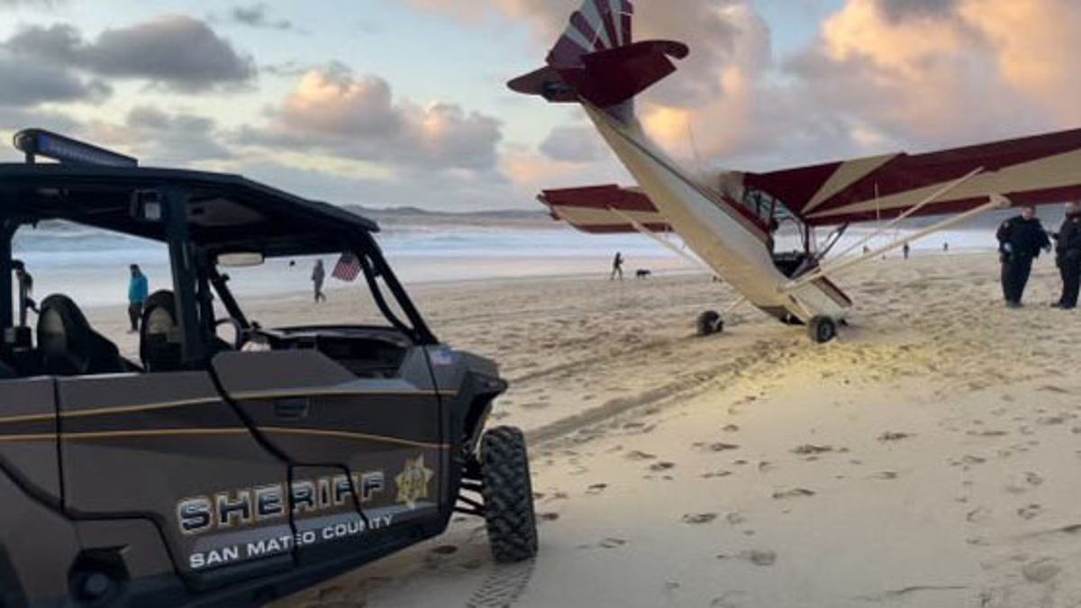 A small airplane with its nose in the sand on a beach