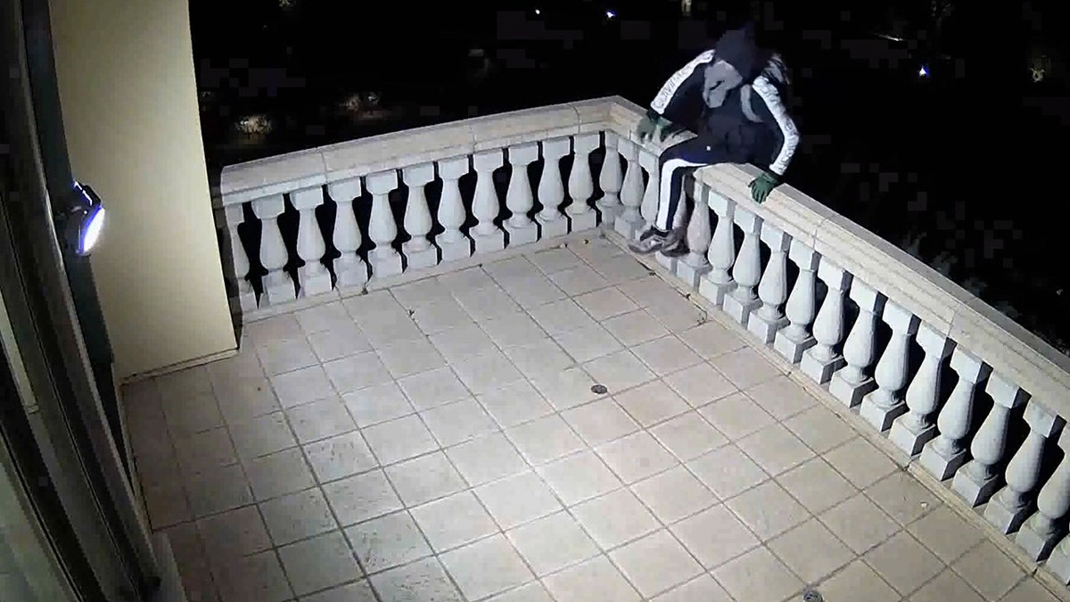 Thief climbing over balcony railing