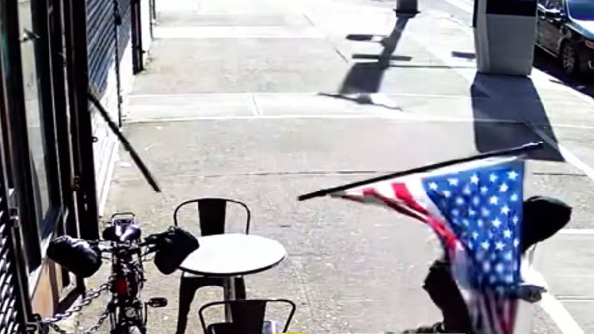 An arson suspect falling off a table grabbing an Israeli and US flag