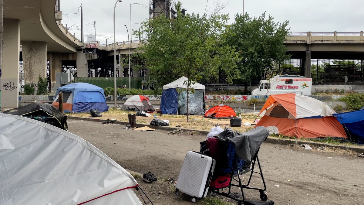 Tents and other belongings cover a grassy area in Portland